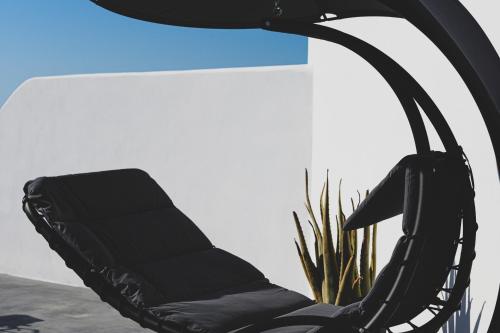 a black chair sitting next to a plant at Santolia Art Suites in Oia