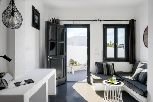 a white living room with a couch and a table at Santolia Art Suites in Oia