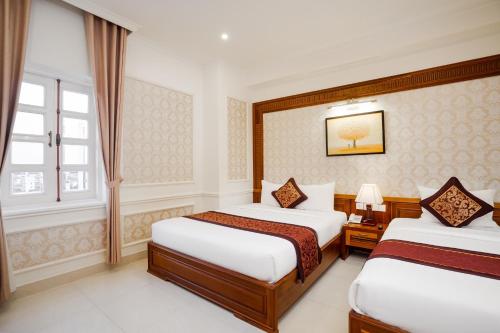 a hotel room with two beds and a window at Riverside Hotel Quang Binh in Dong Hoi