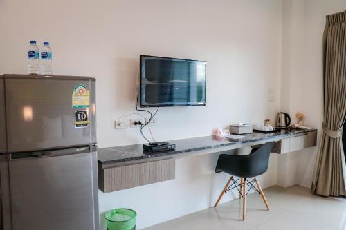 a kitchen with a desk with a television and a chair at S2 Airport Residence in Nai Yang Beach