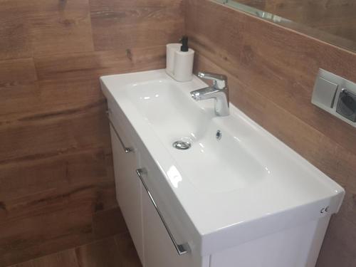a bathroom with a white sink and a wooden wall at Apartament Młynarska - indywidualny dostęp in Piaseczno