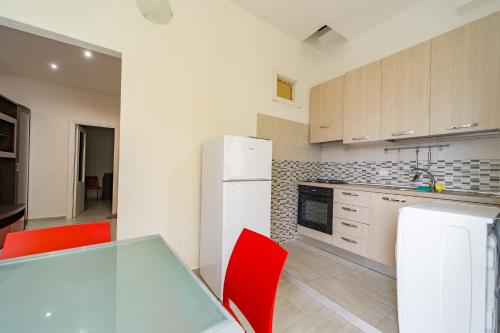 eine Küche mit einem weißen Kühlschrank und roten Stühlen in der Unterkunft Naranji House Red Relax in Altavilla Milicia