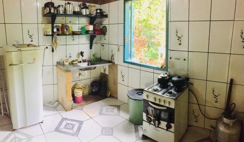 a small kitchen with a stove and a sink at Sítio Refúgio do Eneas - Vista para o Mar in Parati-Mirim