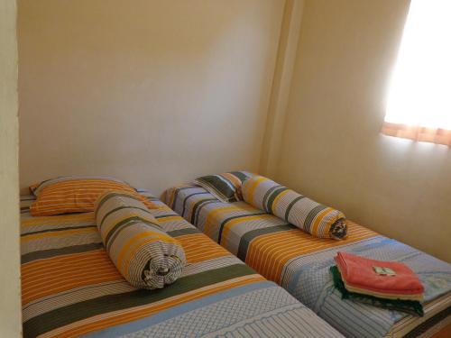 two twin beds in a corner of a room at Hotel Musafir Inn in Padang