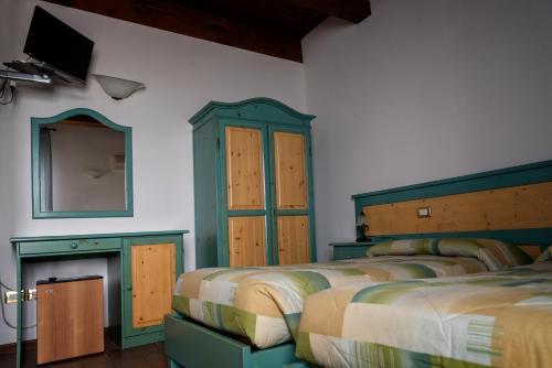 una camera con 3 letti, uno specchio e una TV di La Locanda dei Gagliardi a Lugo