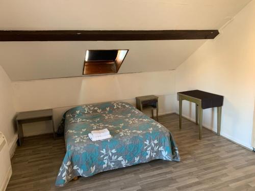 a small bedroom with a bed and a table at hôtel Le Cosy in Pont-de-Chéruy