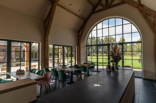 een eetkamer met tafels en stoelen en grote ramen bij Casa Cava B&B in Dendermonde