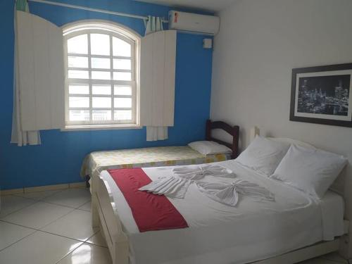 1 dormitorio con 2 camas y ventana en Pousada Garota De Itauna en Saquarema