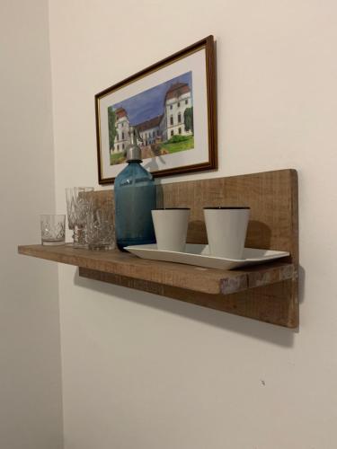 una estantería de madera con dos tazas y un jarrón. en Anna Apartman, en Pápa