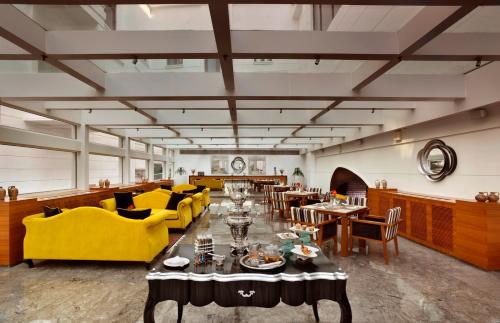 a restaurant with yellow furniture and tables and chairs at The Lalit Great Eastern Kolkata in Kolkata