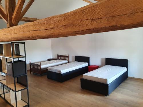 a room with three beds and a wooden ceiling at Gîte Le Bonnet in Marlieux