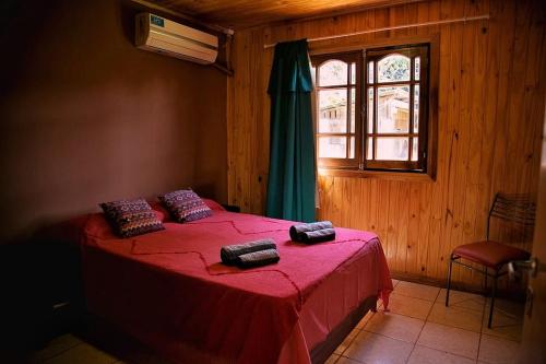 a bedroom with a red bed with a window at FRIDA in Puerto Iguazú