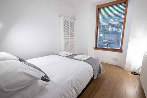 ein weißes Bett in einem Zimmer mit Fenster in der Unterkunft ☆ Spacious 2 Bed flat, Close to University ☆ in Dundee