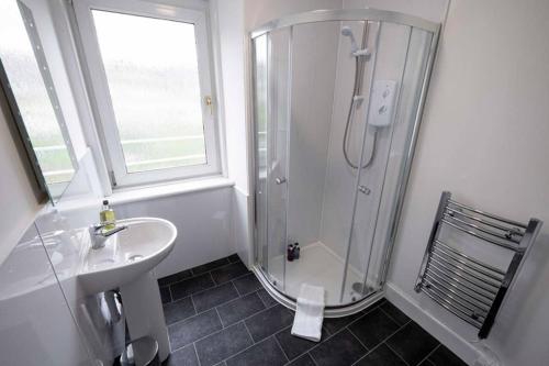 a white bathroom with a shower and a sink at ☆ Bright, Modern West-End Apartment ☆ in Dundee