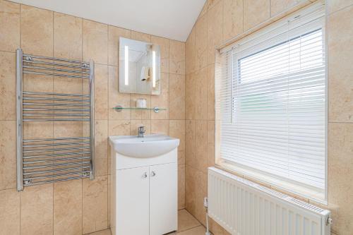 a bathroom with a sink and a mirror and a window at The Richmond Bed and Breakfast - Adults only in Shanklin
