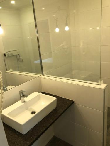 a white bathroom with a sink and a mirror at Corso, Zimmer & Cafe, Hotel Garni in Pressbaum