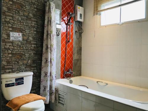 La salle de bains est pourvue d'une baignoire, de toilettes et d'une fenêtre. dans l'établissement Baan Sang Singh, à Chiang Mai