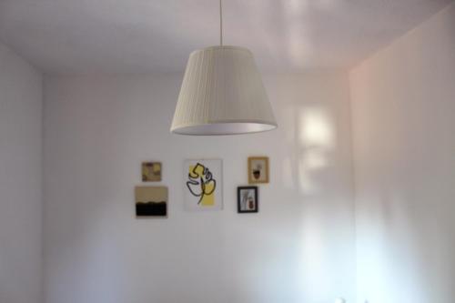 a white room with a lamp and pictures on the wall at Apartman Marija in Lopar