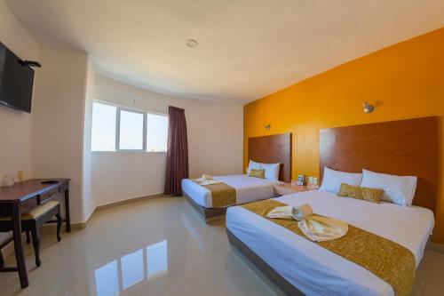 a hotel room with two beds and a desk at Hotel Maria del Rocio in Veracruz