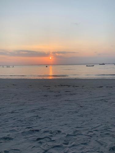 a beach with the sun setting in the water at Hostel Encantadas Ecologic in Ilha do Mel