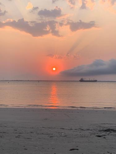 a sunset on the beach with a ship in the ocean at Hostel Encantadas Ecologic in Ilha do Mel