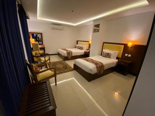 a hotel room with two beds and a chair at Grand Mongolia Hotel in Rawalpindi