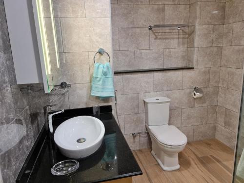 a bathroom with a toilet and a sink and a mirror at Royale Suites by Arc Royal Luxury Apts in Anse Royale