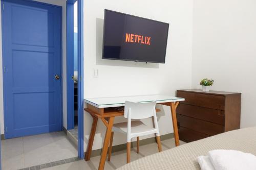a bedroom with a desk and a tv on a wall at Hotel Azulado Jericó in Jericó