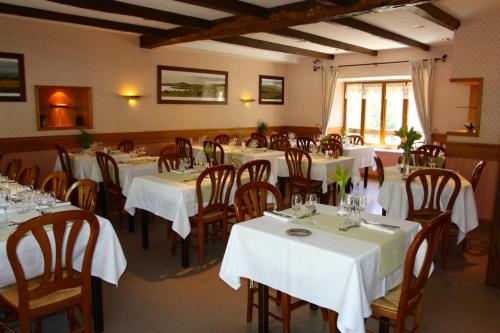 un restaurante con mesas y sillas con manteles blancos en Hôtel des Voyageurs en Saint-Chély-dʼAubrac