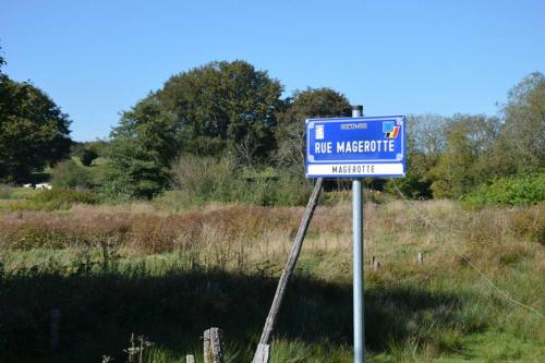 a blue sign in the middle of a field at La cense du vieux frêne in Sainte-Ode