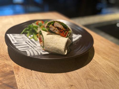 a black plate with a burrito and salad on a table at Holiday Inn Newcastle-Jesmond by IHG in Newcastle upon Tyne