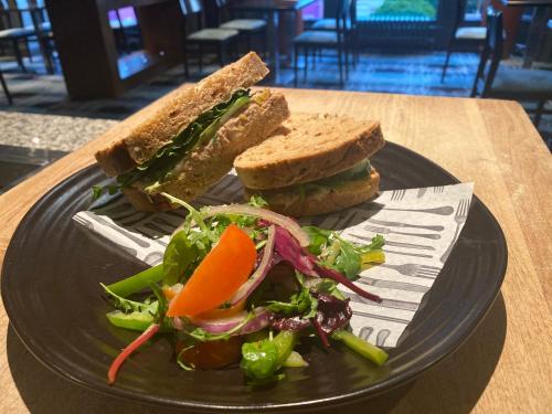 a black plate with a sandwich and salad on a table at Holiday Inn Newcastle-Jesmond by IHG in Newcastle upon Tyne
