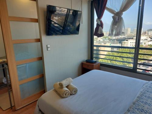 a bedroom with a bed and a large window at Departamento Metro Parque Bustamante in Santiago