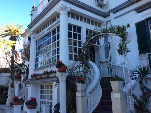 Albergo Santa Teresa في توري دل غريكو: منزل أبيض مع نباتات الفخار على الدرج