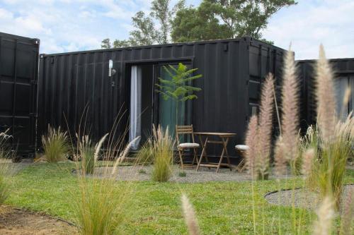 a black tiny house with a table in a garden at La Finca de Vane in Valle de Guadalupe