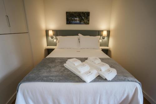 a bedroom with a bed with two towels on it at Casa do Engenho Braga - Apartamentos com Vista Rio & SPA in Braga