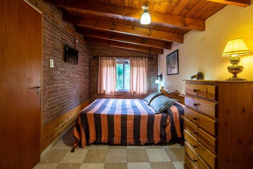 - une chambre avec un lit et un mur en briques dans l'établissement El Chañar, à Villa General Belgrano