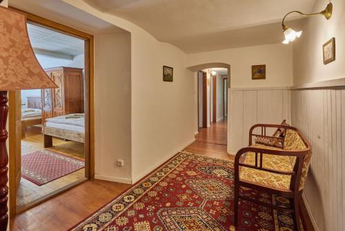a living room with a chair and a bedroom at POD SVATOU ANNOU - penzion a řízkovna in Horní Maršov