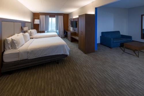 um quarto de hotel com uma cama e uma cadeira azul em Holiday Inn Express Hotel & Suites Louisville South-Hillview, an IHG Hotel em Hillview