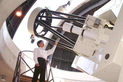 a man standing in front of a telescope in a building at Minami Aso Luna Observatory Auberge Mori no Atelier in Minami Aso