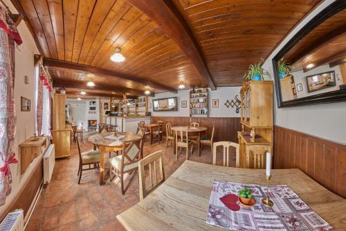 a restaurant with wooden ceilings and tables and chairs at POD SVATOU ANNOU - penzion a řízkovna in Horní Maršov