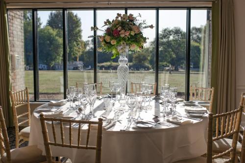 a white table with a vase of flowers and glasses at voco Oxford Thames by IHG in Oxford