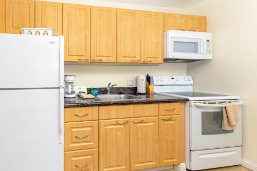 a kitchen with wooden cabinets and a white refrigerator at Mountain Views & Steps to Beach - Free Parking! in Honolulu