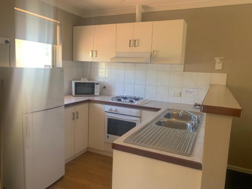 a kitchen with white cabinets and a sink and a microwave at Waratah in Albany