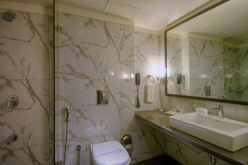 a bathroom with a sink and a toilet and a mirror at The President-A Boutique Hotel in Ahmedabad