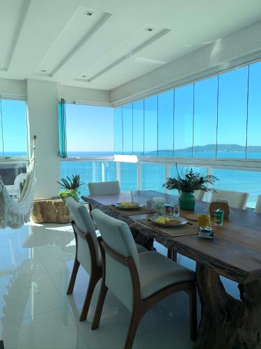 comedor con mesa de madera y sillas en COBERTURA com belíssima vista para o mar e jacuzzi, en Itapema