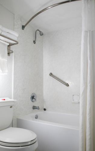 a white bathroom with a toilet and a bath tub at Days Inn by Wyndham Stuart in Stuart