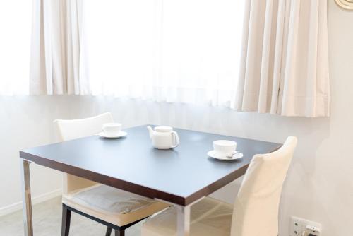 a dining room table with two cups and chairs at Pangoo Shinagawa in Tokyo