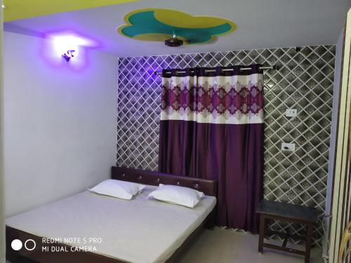 New Hotel Yatri Niwas في فاراناسي: غرفة نوم بسرير وستارة ارجوانية