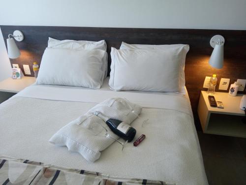 a hotel room with a bed with a phone on it at Flat Suites em Hotel de Luxo in Maceió